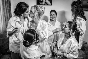Black and white candid photo of bridal party in matching robes getting ready.