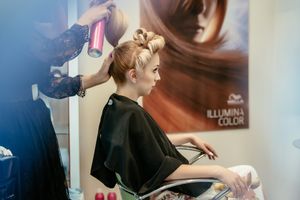 Bride getting her hair styled in salon chair with professional stylist.