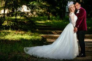 Romantic wedding portrait of couple on garden steps with sunlit background.
