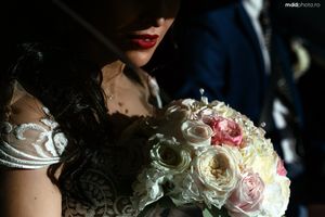 Close-up of bridal bouquet with white and pink roses in dramatic lighting.