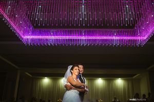 Couple dancing under purple LED chandelier lighting at reception venue.