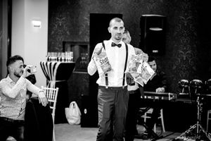 Performer in suspenders and bow tie entertaining guests at a black and white wedding reception.