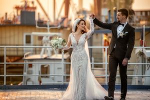 Newlyweds pose together on dock during golden hour with industrial backdrop.