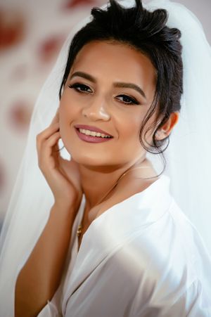 Bridal portrait showing elegant makeup and white robe during wedding preparations.