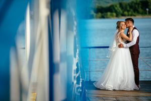 Artistic wedding portrait framed through a blue-tinted window reflection.