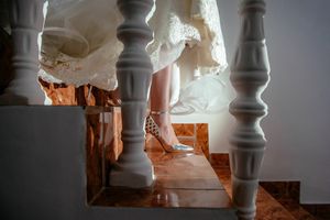 Wedding dress detail through white balusters on stairs with natural lighting.