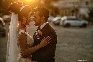 A romantic wedding couple embraces during golden hour sunset in an outdoor urban setting.