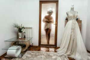 Wedding dress display in boutique with mirror reflection and decorative elements.