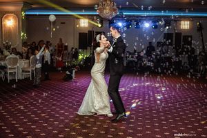 A couple shares their first dance on an illuminated dance floor at their wedding reception.