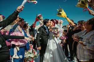 Wedding guests toss colorful ribbons and celebrate under bright blue sky.