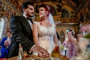 Wedding ceremony in an ornate baroque church with detailed ceiling frescoes.