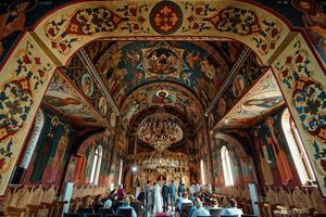 Elegant wedding ceremony taking place in a richly decorated cathedral with painted walls and chandeliers.