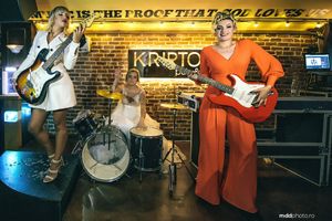 Musicians perform on stage with guitars and drums at wedding reception.
