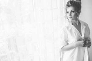 High key black and white bridal portrait near window with soft lighting.