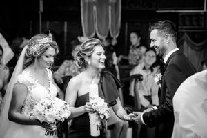 A joyful moment during a wedding ceremony with bouquets and laughter shared between attendees.