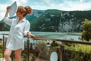 Woman in white shirt overlooking scenic mountain lake landscape.