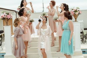 Group of women in pastel dresses celebrating by a pool with floral decorations.
