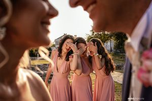 Bridesmaids in pink dresses sharing a joyful moment during an outdoor wedding celebration.
