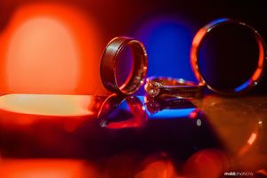 Close-up shot of wedding rings with dramatic red and blue lighting effects.