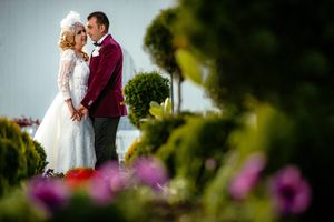 Romantic garden wedding portrait with purple flowers in the foreground.