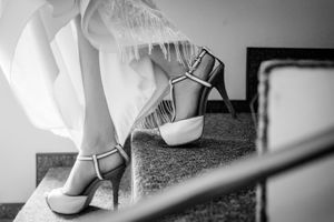 Close-up black and white photo of elegant bridal shoes on a textured surface.