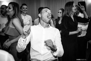 Black and white candid shot of guests dancing and celebrating at a wedding reception.