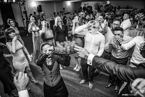 Wedding guests dancing energetically at a reception celebration in black and white.