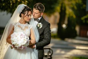 Romantic wedding portrait of couple with bouquet in outdoor setting.