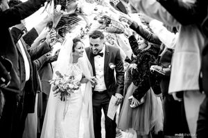 Newlywed couple walking under guest tunnel at wedding celebration.