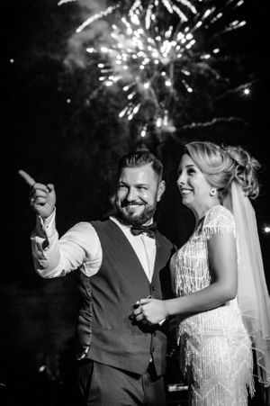 A couple celebrates their wedding night under spectacular fireworks in an elegant black and white photo.