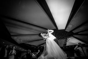 A wedding couple dances under a draped tent ceiling during their reception celebration.