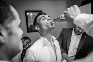 Candid moment of celebratory drink during wedding preparations.