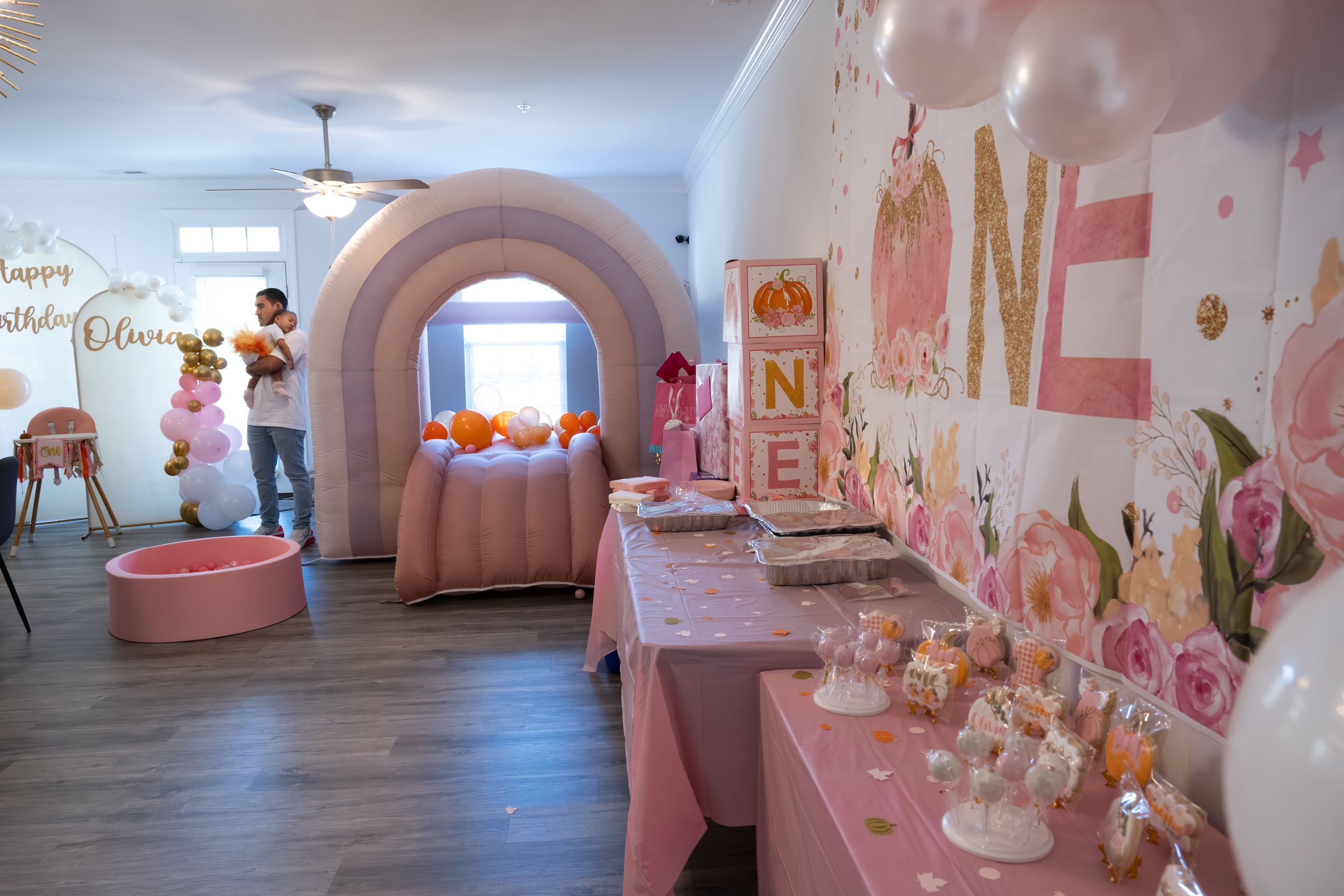 Pink-themed party room with arched doorway, decorated tables, and festive wall displays.