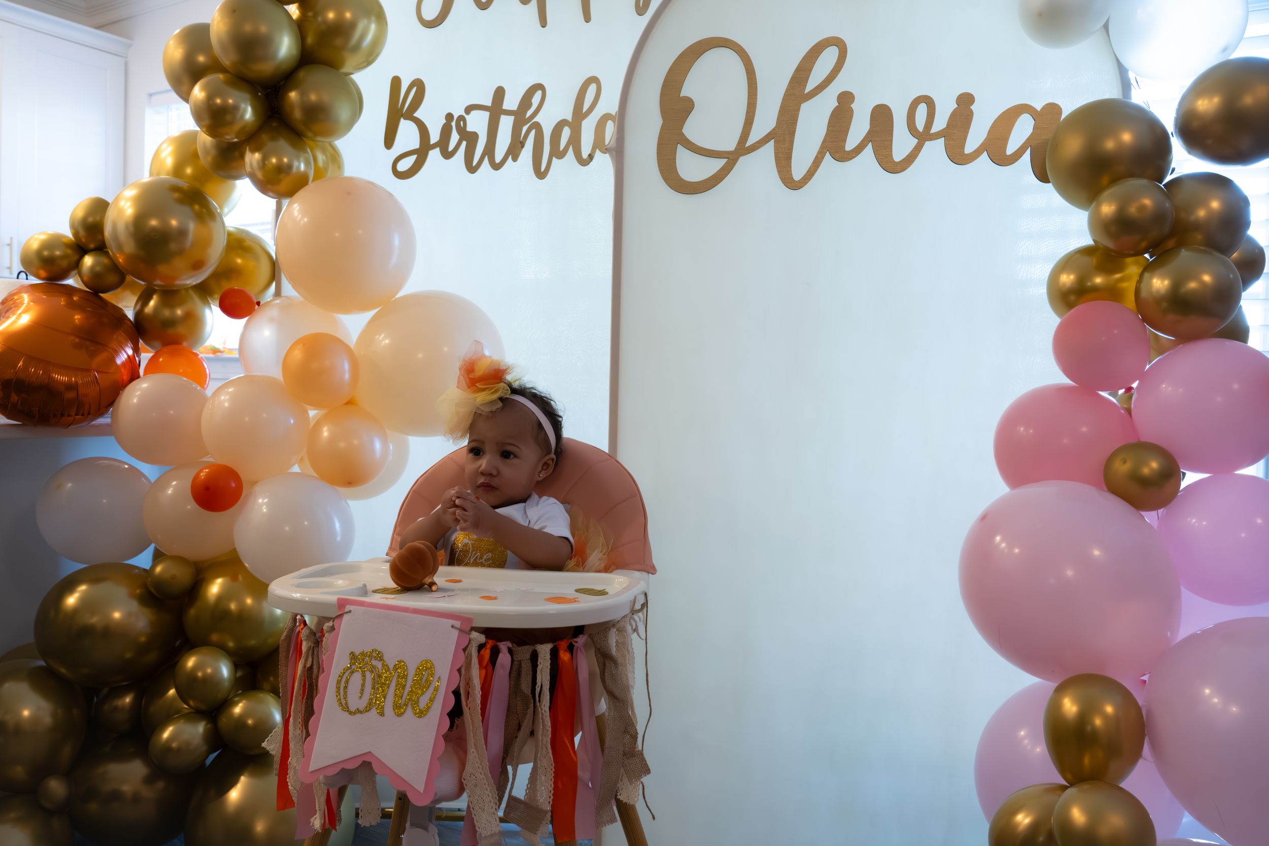 Elegant balloon arch with gold and pink balloons frames a birthday sign for Olivia.