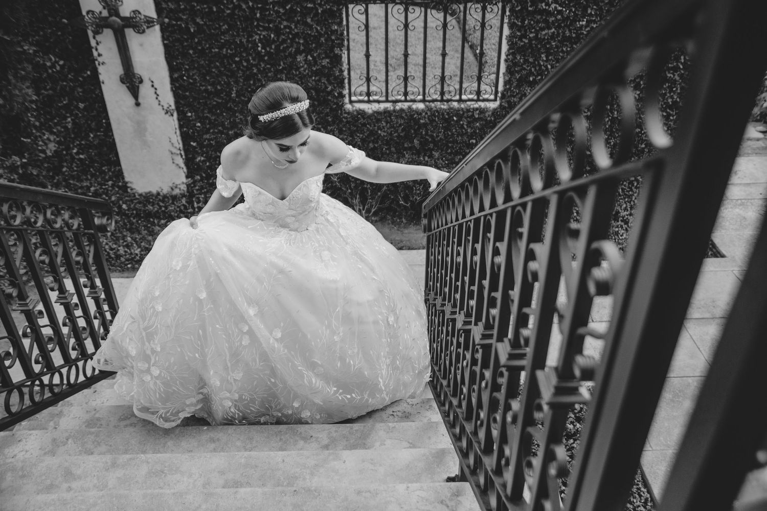 Black and white portrait on historic staircase with ornate iron railings.