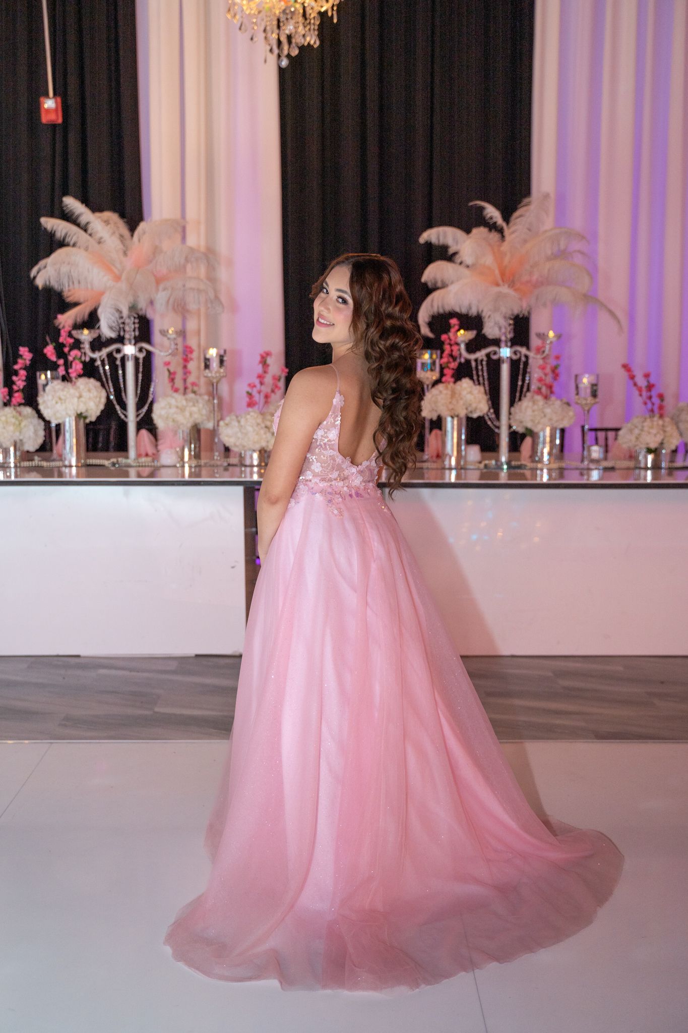 Elegant ballroom decorated with pink tulle, feathers and crystal chandeliers for a formal event.