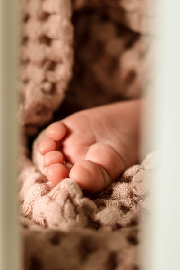 Baby foot sticking out of the blanket in the crib