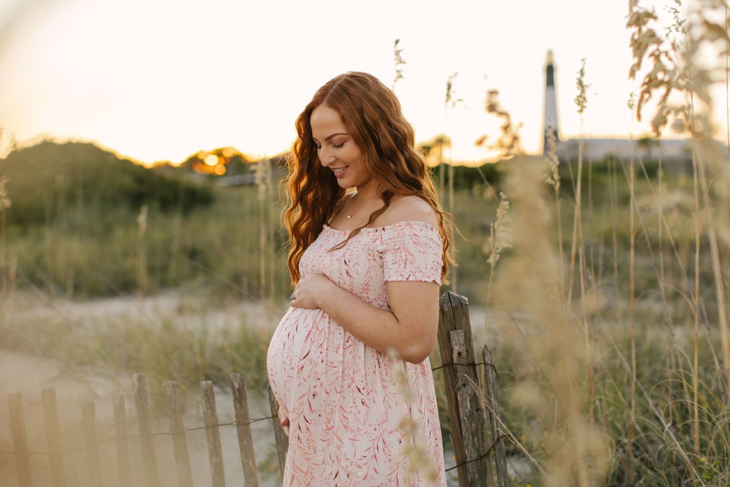 A maternity portrait of an expectant mother in a lace dress at sunset.