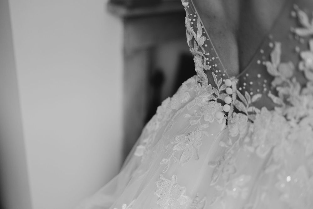 Close-up detail of delicate lace and beading on white wedding dress bodice.