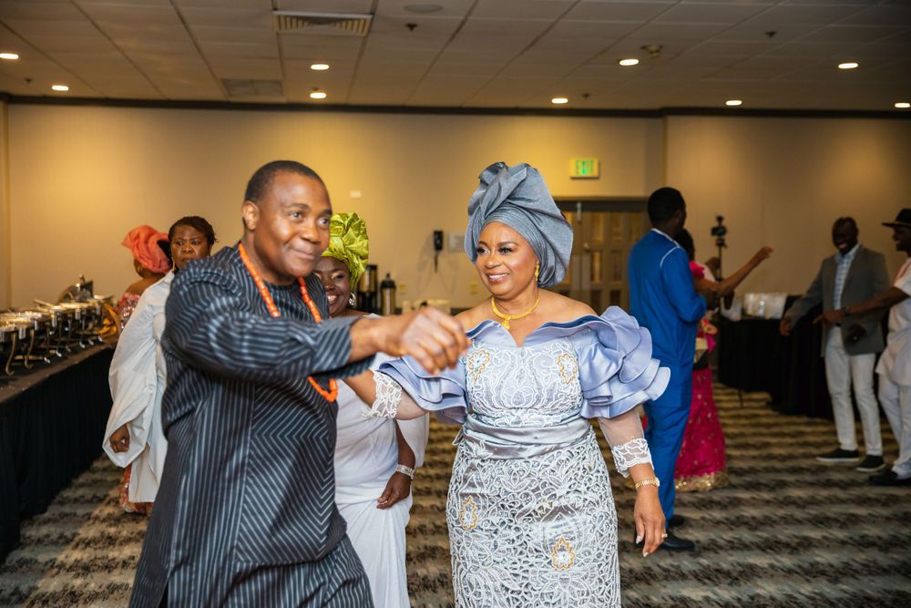 Guests dancing and celebrating at formal event wearing traditional African attire.