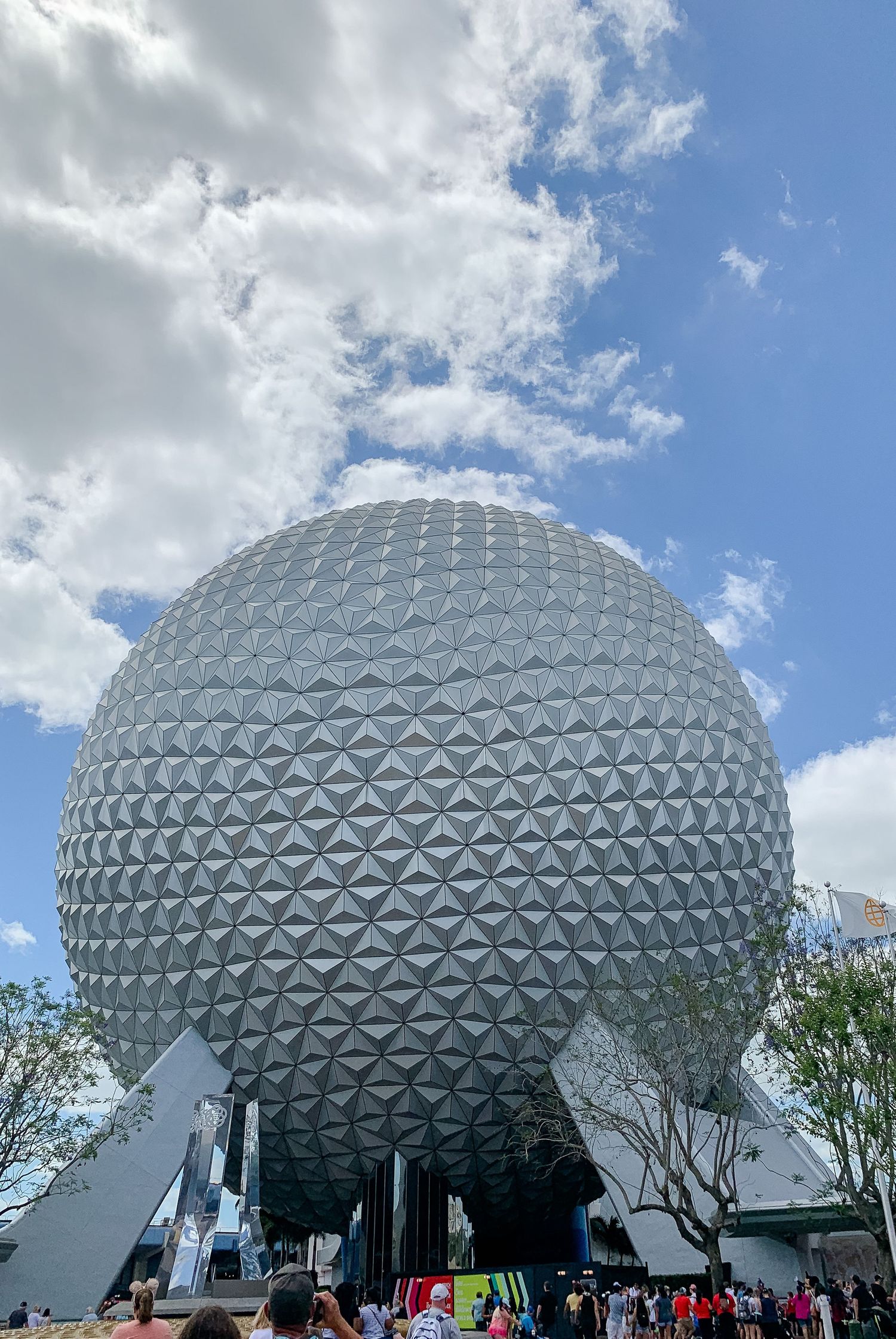 Spaceship Earth, the iconic geodesic sphere at EPCOT theme park, stands against a blue sky with white clouds.