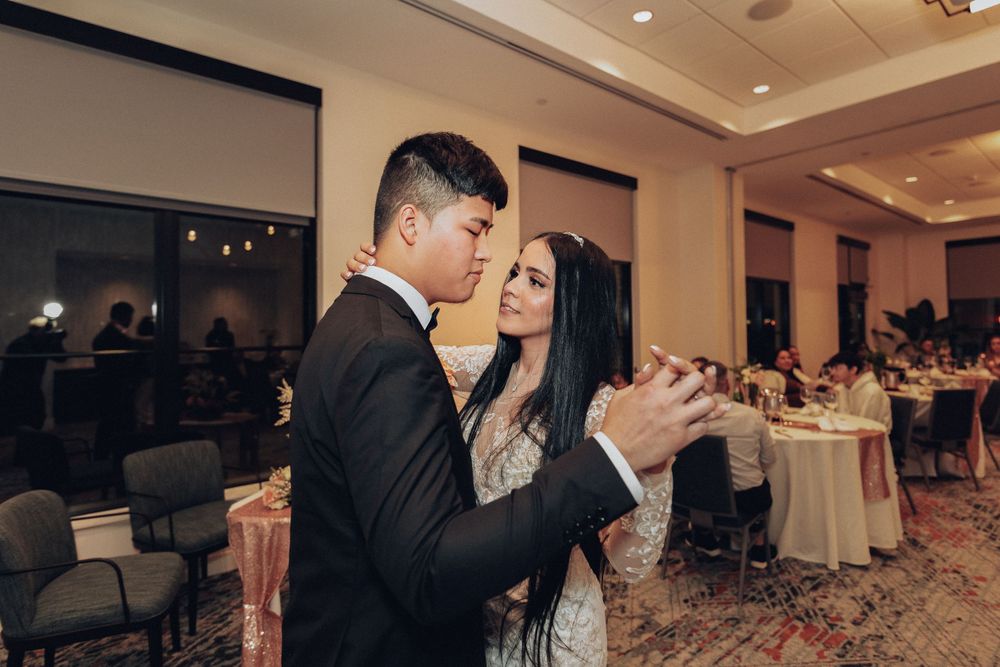 A couple shares their first dance in an elegant reception hall with ambient lighting.