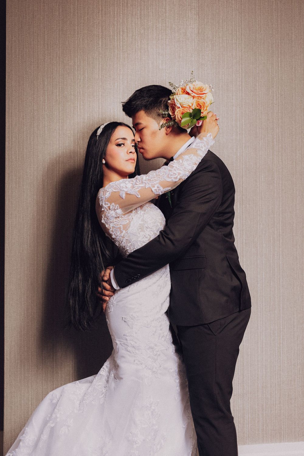 Elegant wedding portrait featuring couple in classic dress and suit with floral accents.