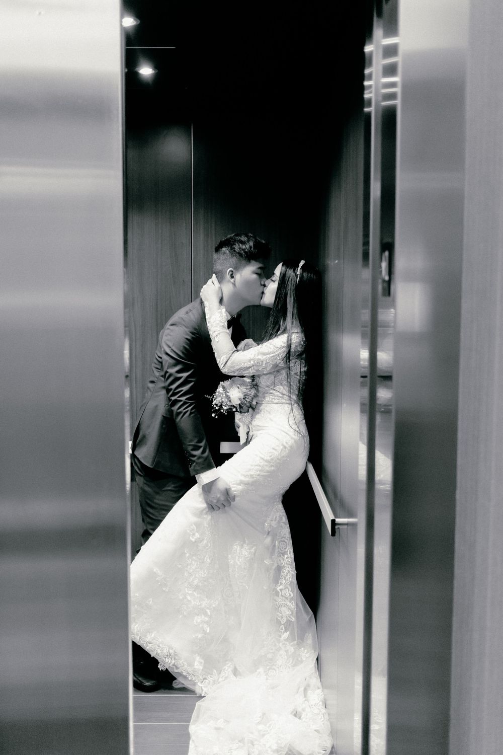 A romantic black and white elevator wedding photo capturing an intimate moment.