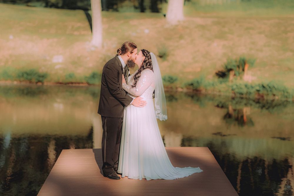 A romantic wedding portrait of a couple on a dock by a lake.
