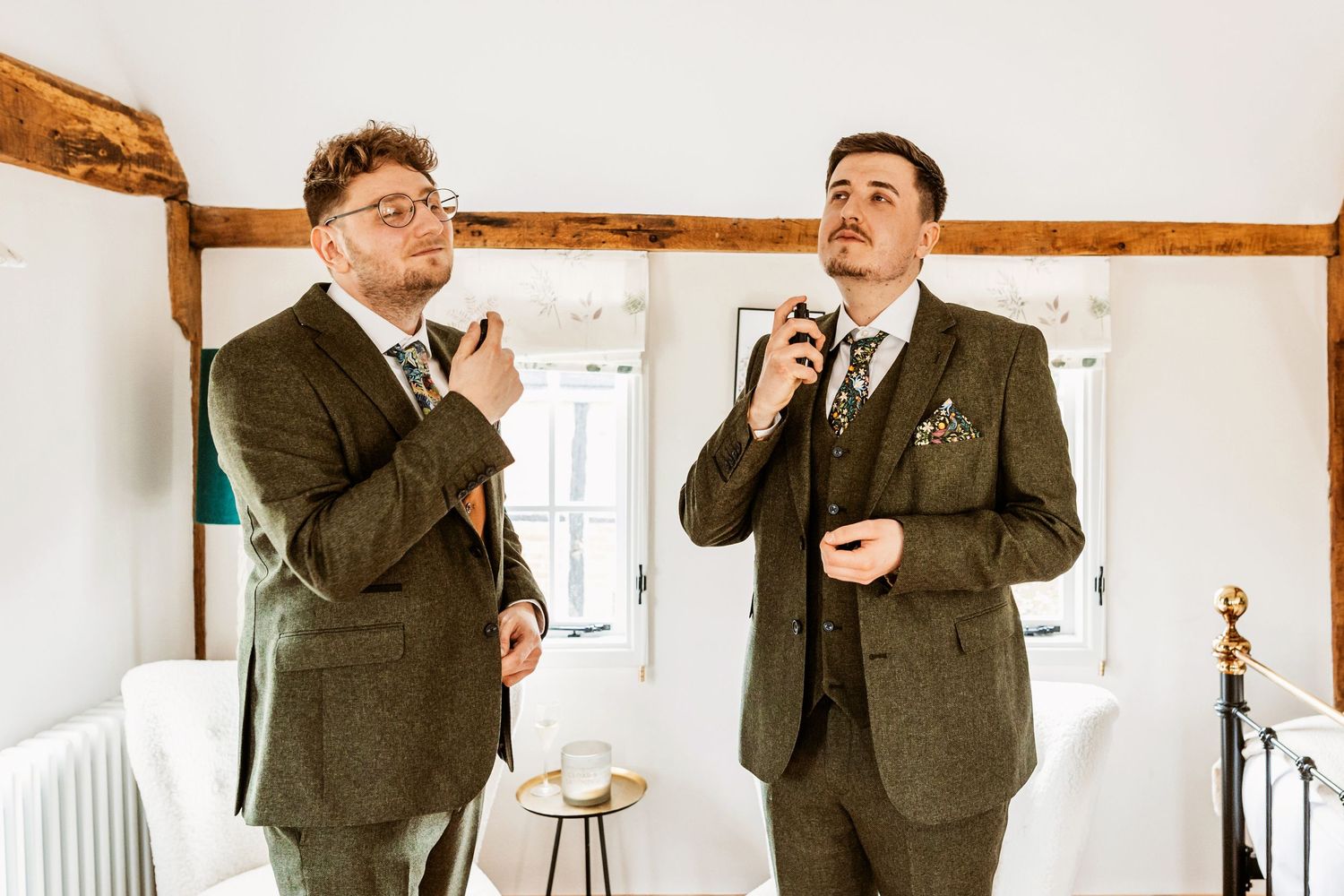 Two groomsmen in tweed suits sharing a playful moment during wedding preparations.
