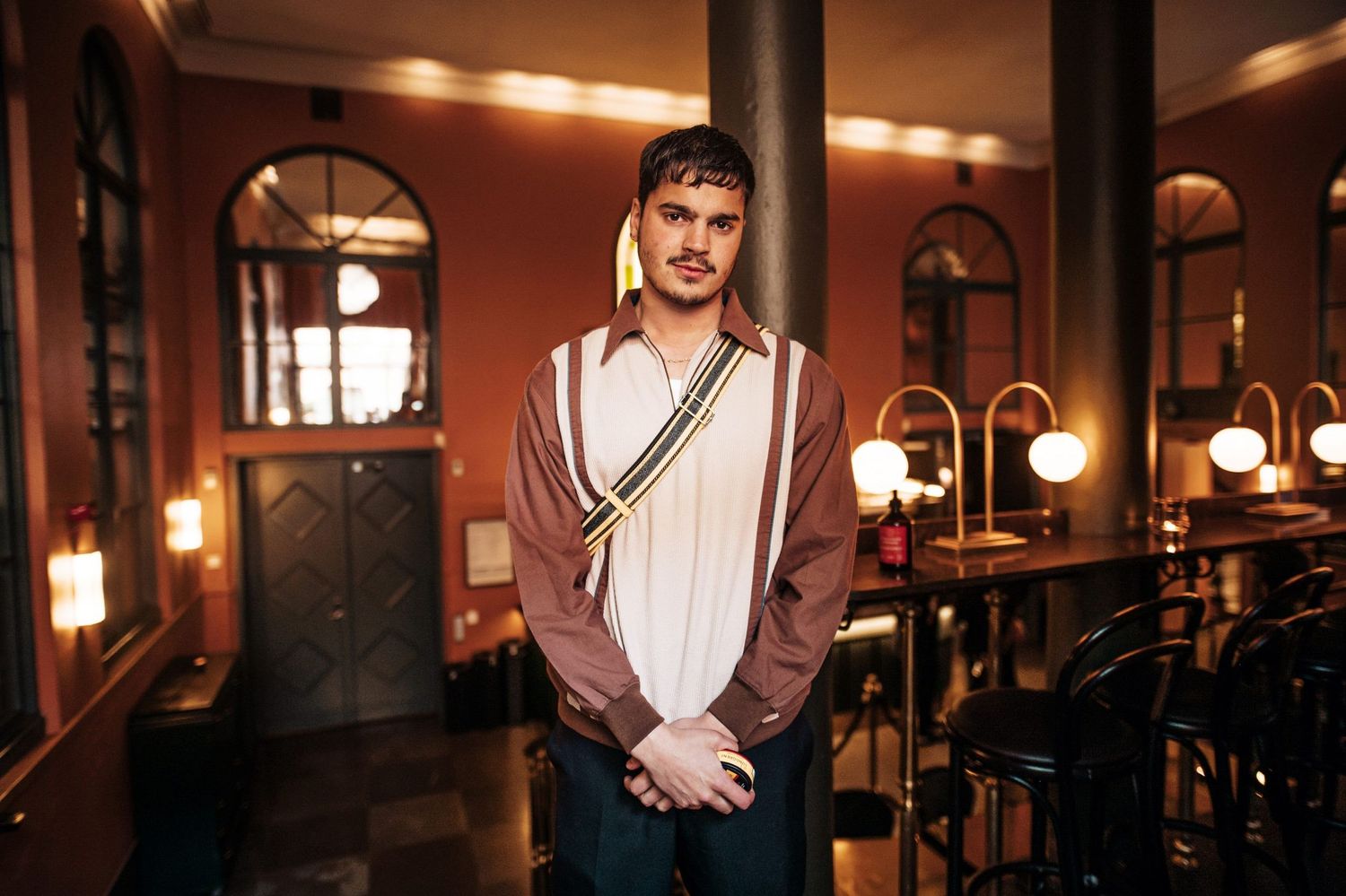 Interior portrait in a warmly lit restaurant with arched windows and vintage decor.