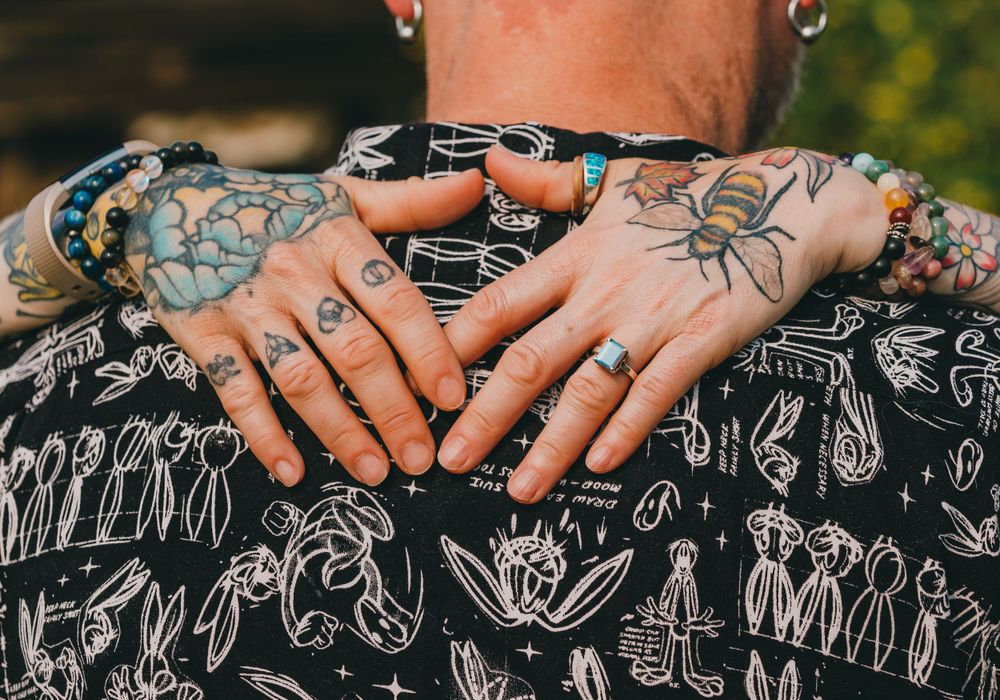 Close-up of tattooed hands resting on a patterned black and white shirt.