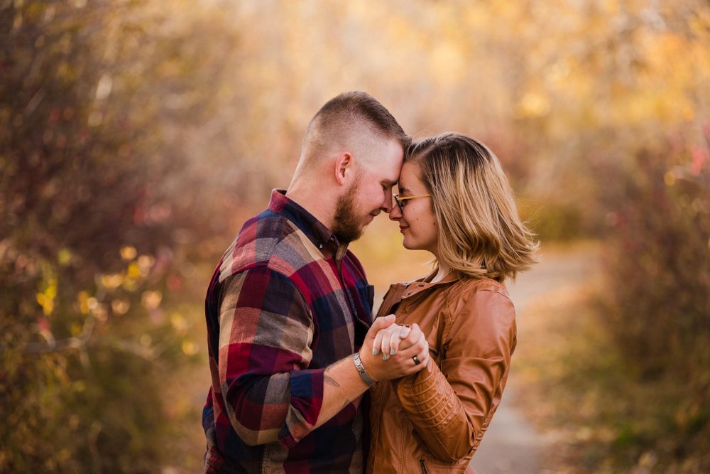 Intimate couple portrait with soft golden light and autumn foliage backdrop.