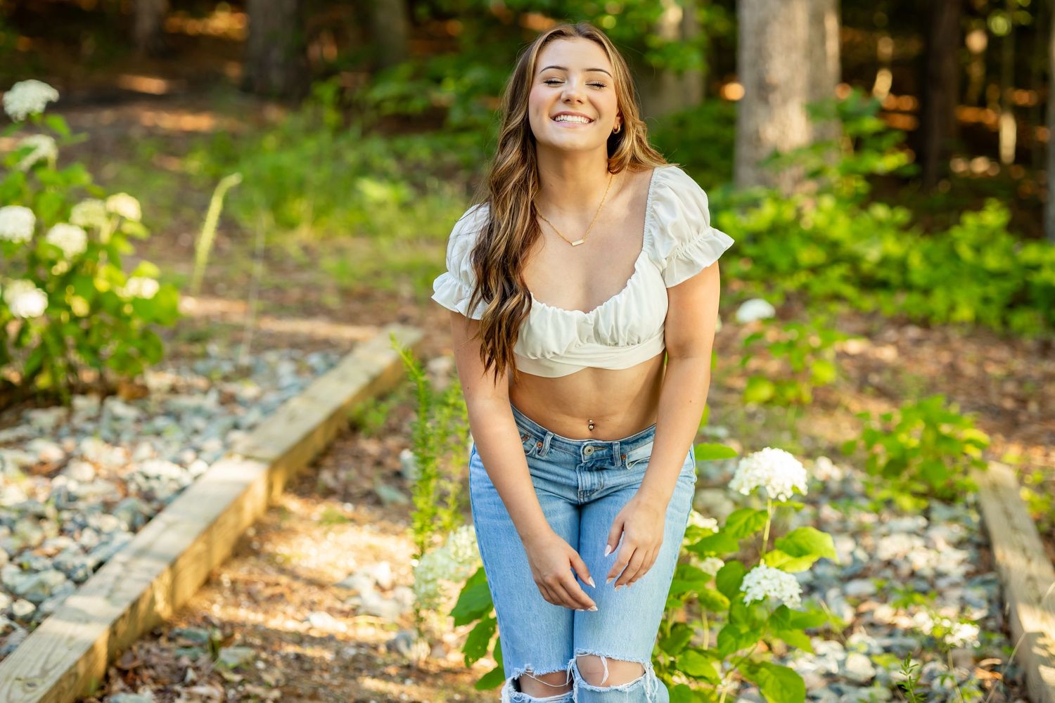 Casual summer portrait on gravel path with distressed jeans and white top.